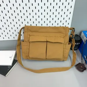 Close-up of mustard yellow canvas messenger bag featuring dual front pockets and side pockets