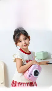 Pink camera-shaped kids chest bag worn by a young girl with black lens details