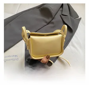 Detail of pale yellow mini crossbody bag with metal logo and sleek leather texture