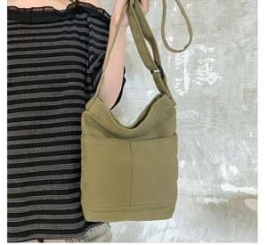 Detail of army green canvas shoulder bag with dual front pockets and adjustable strap