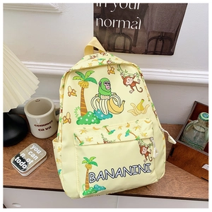 Close-up of cute yellow kids backpack with cartoon monkey and banana prints and logo