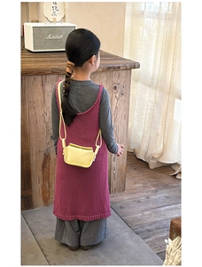 Detail shot of a bright yellow leather mini crossbody bag for kids in a cozy interior