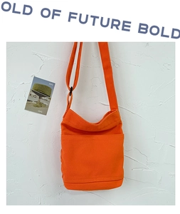 Detail of orange canvas bag featuring textured fabric and adjustable shoulder strap
