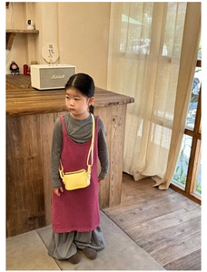 Detail of a bright yellow leather mini crossbody bag styled with a girls rose knit dress