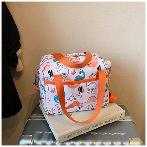 Detail of white cartoon dinosaur storage bag with orange handles on a silver suitcase