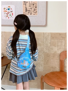 Mädchen trägt eine blaue Cartoon-Brusttasche mit lustigen Prints in einem Innenraum