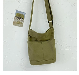 Detail view of olive green canvas shoulder bag with adjustable strap and front pocket
