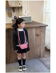 Detail shot of a little girl wearing a pink flap crossbody bag with a black stylish outfit