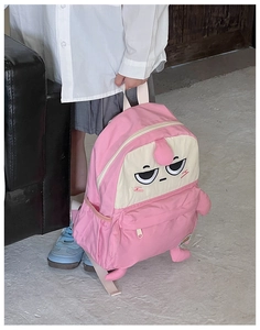 Detailed shot of pink cartoon schoolbag with funny 3D limbs and embroidery details