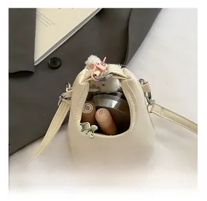 Vue détaillée de l'intérieur d'un mini sac en cuir crème avec rouge à lèvres et bijoux