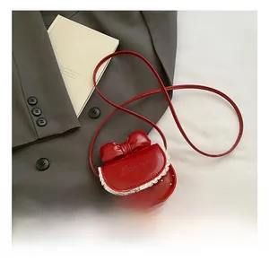 Détail du mini sac rouge avec nœud, dentelle blanche et finition brillante