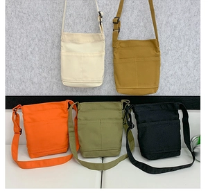Detail of colorful canvas crossbody phone bags featuring front pockets and adjustable straps