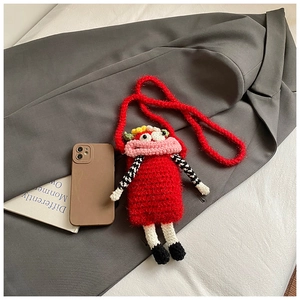 Detail of red crochet doll coin purse with cartoon eyes and pink lips on a grey suit