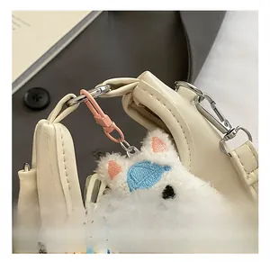 Détail de la mini sacoche blanche avec boucle argentée et charm chat en peluche