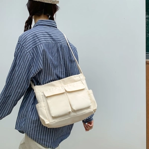 Minimalist off-white canvas tote bag with multi-pocket design shown on model shoulder