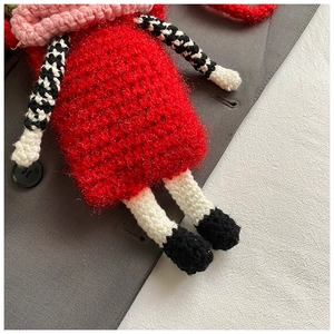 Detailed view of handmade crochet doll charm with vibrant red yarn and texture details