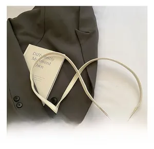 Détail du mini sac en cuir crème avec bandoulière réglable et breloque ours en peluche