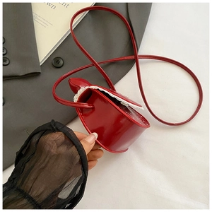 Gros plan d'un mini sac à bandoulière rouge en cœur avec bordure en dentelle blanche