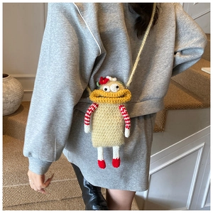 Detail of a handmade crochet cartoon character crossbody bag with long limbs on a model