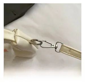 Vue macro du mousqueton en métal argenté et de la bandoulière d'un sac crème pour enfant