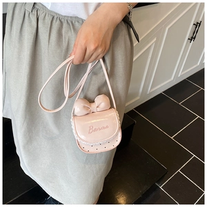 Gros plan du mini sac rose avec nœud, dentelle et broderie Barma sur le côté