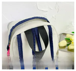 Detail of the navy blue and black woven handle on a cream nylon backpack