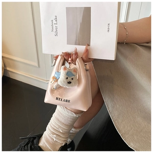 Détail du sac à main rose brillant avec pendentif chien en peluche et motif de lettres
