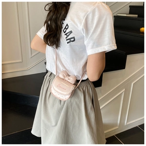 Détail d'un sac bandoulière rose avec nœud, bordure en dentelle et finition vernie
