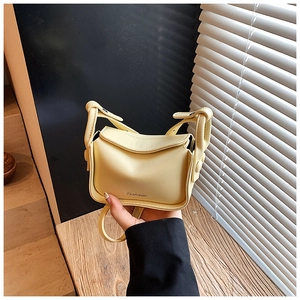 Detail of a creamy yellow mini crossbody bag with a Fashion metal buckle and knotted strap