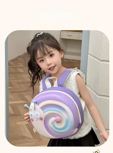 Toddler model wearing the 3D snail hardshell backpack in purple with strawberry detail