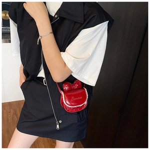 Détail d'un mini sac bandoulière rouge avec gros nœud et bordure en dentelle blanche