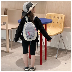 Detail of lightweight color-block nylon backpack with pink zippers and blue drawstring cords
