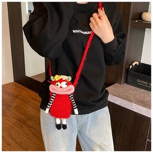 Detail of red crochet monster bag with cartoon features and striped limbs on a model
