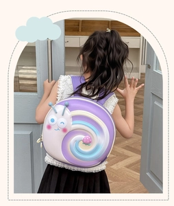 Detail of cute purple snail backpack with rainbow spiral shell on a child's back