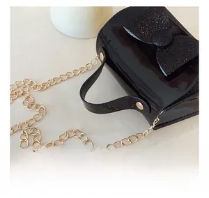 Detail of sequin bow on black patent leather girls handbag with gold chain strap