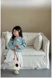 Gros plan d'un sac bandoulière blanc en peluche chiot sur un pull en maille
