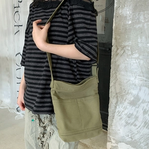 Minimalist olive green canvas shoulder bag with external pockets shown on model