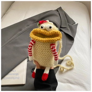 Detail of handmade crochet monster bag with yellow big mouth and red feet accents