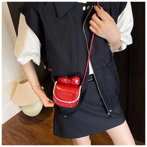 Détail d'un mini sac rouge avec nœud et bordure en dentelle blanche sur tenue noire