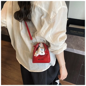 Détail d'un mini sac bandoulière en cuir verni rouge avec pendentif en peluche