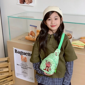 Grüne Kinder-Brusttasche mit Monster-Print in einer gemütlichen Bäckerei-Szene
