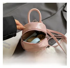Intérieur du mini sac à dos rose montrant l'espace pour téléphone et pompon blanc