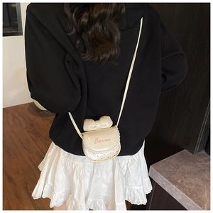 Détail du mini sac crème avec nœud, logo Banma, bordure en dentelle et cuir verni brillant