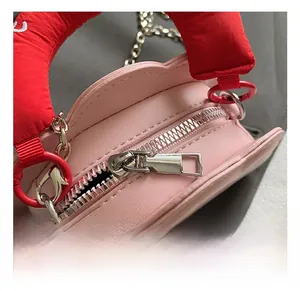 Detail show of pink cloud bag with red padded handle and silver metal zipper hardware