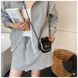 Détail d'un mini sac noir à nœud avec bordure en dentelle et finition en cuir verni