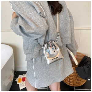 Détail du mini sac argenté avec logo HELAHE et pendentif mignon en peluche de chien