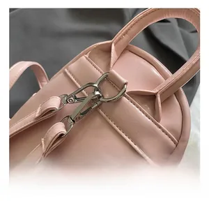 Détail d'un sac à dos rose avec crochets métalliques argentés et finitions soignées