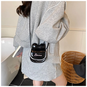 Gros plan du mini sac bandoulière en cuir noir avec bordure en dentelle et nœud chic