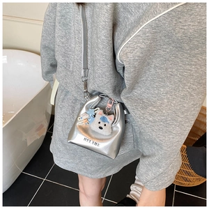 Détail d'un mini sac bandoulière enfant en cuir argenté avec pendentif en peluche mignon