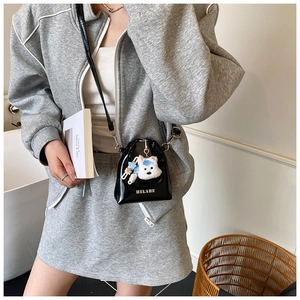Détail du mini sac bandoulière en cuir verni noir avec breloque ours et lettres blanches